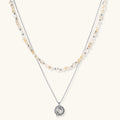 Two-layer necklace with natural stone chips and eco-brass beads, featuring a circular wrapped pendant on cream background.